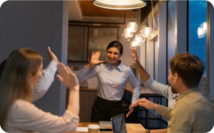 To kvinner gir hverandre en high-five i et kontorlokale. Foto