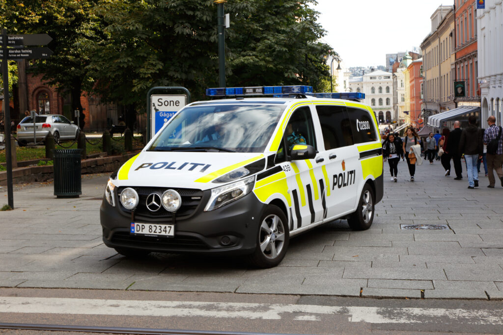 Politibil parkert midt i Karl Johans gate i Oslo. I bakgrunnen ses forbipasserende folk. Foto