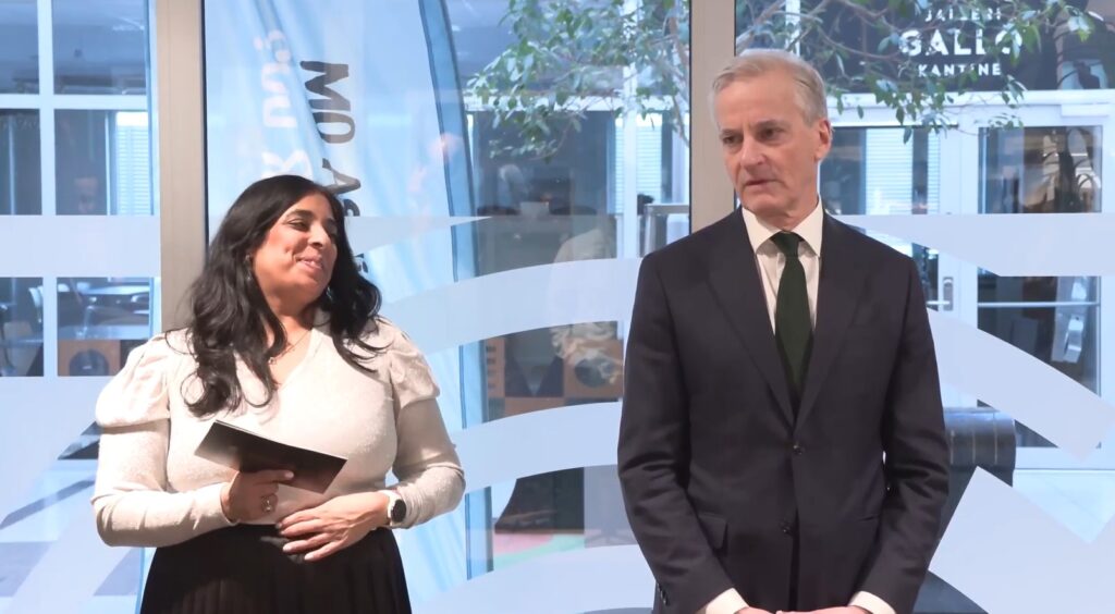 Likestillingsminister Lubna Jaffry iført hvit skjorte og svarte bukser står ved siden av statsminister Jonas Gahr Støre som er kledd i en svart dress med hvit skjorte og slips. Foto