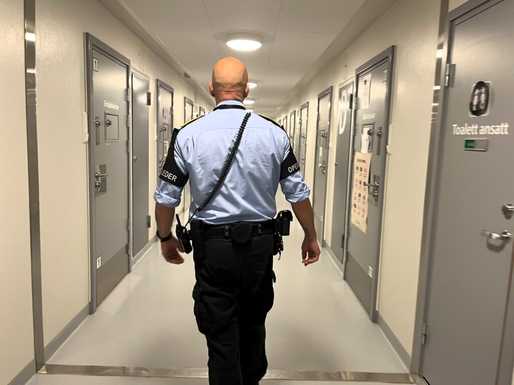 Fengselsbetjent spaserer gjennom en gang på Bredtvet fengsel med ryggen til. Foto