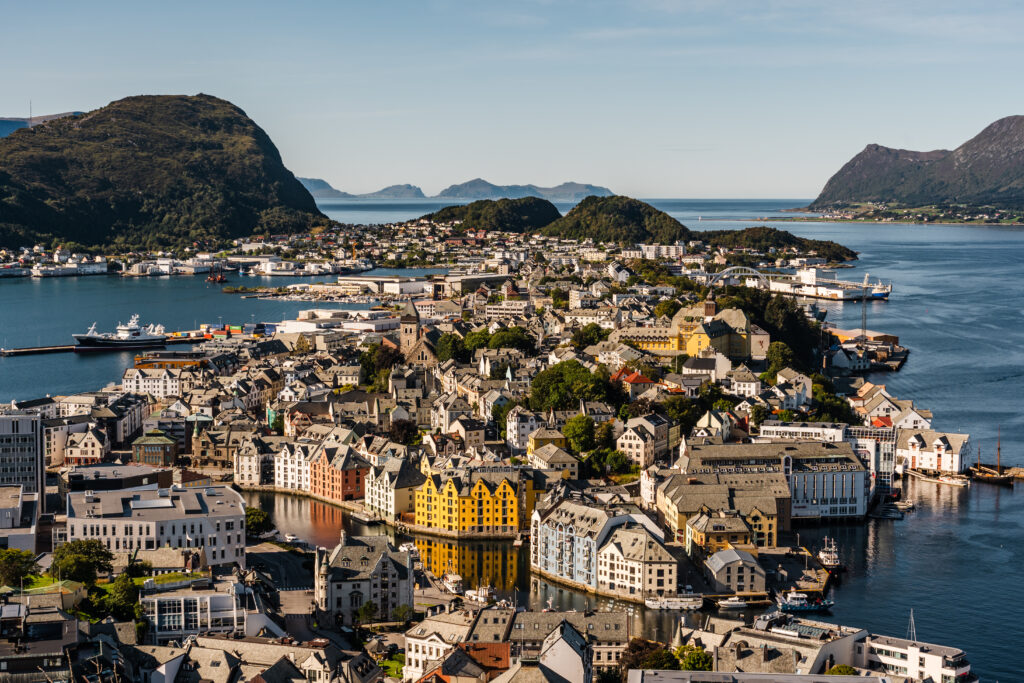 Flyfoto av Ålesund kommune og by med blokkbebyggelse og fjell i bakgrunnen. Foto