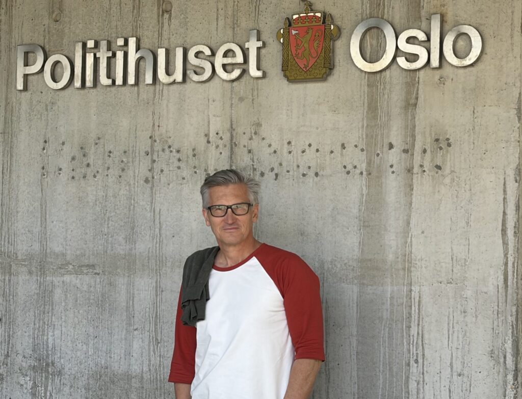 Likestillings- og diskrimineringsombud Bjørn Erik Thon står opp mot en murvegg utenfor Oslo politihus. Over ham henger et skilt hvor det står Politihuset i Oslo.