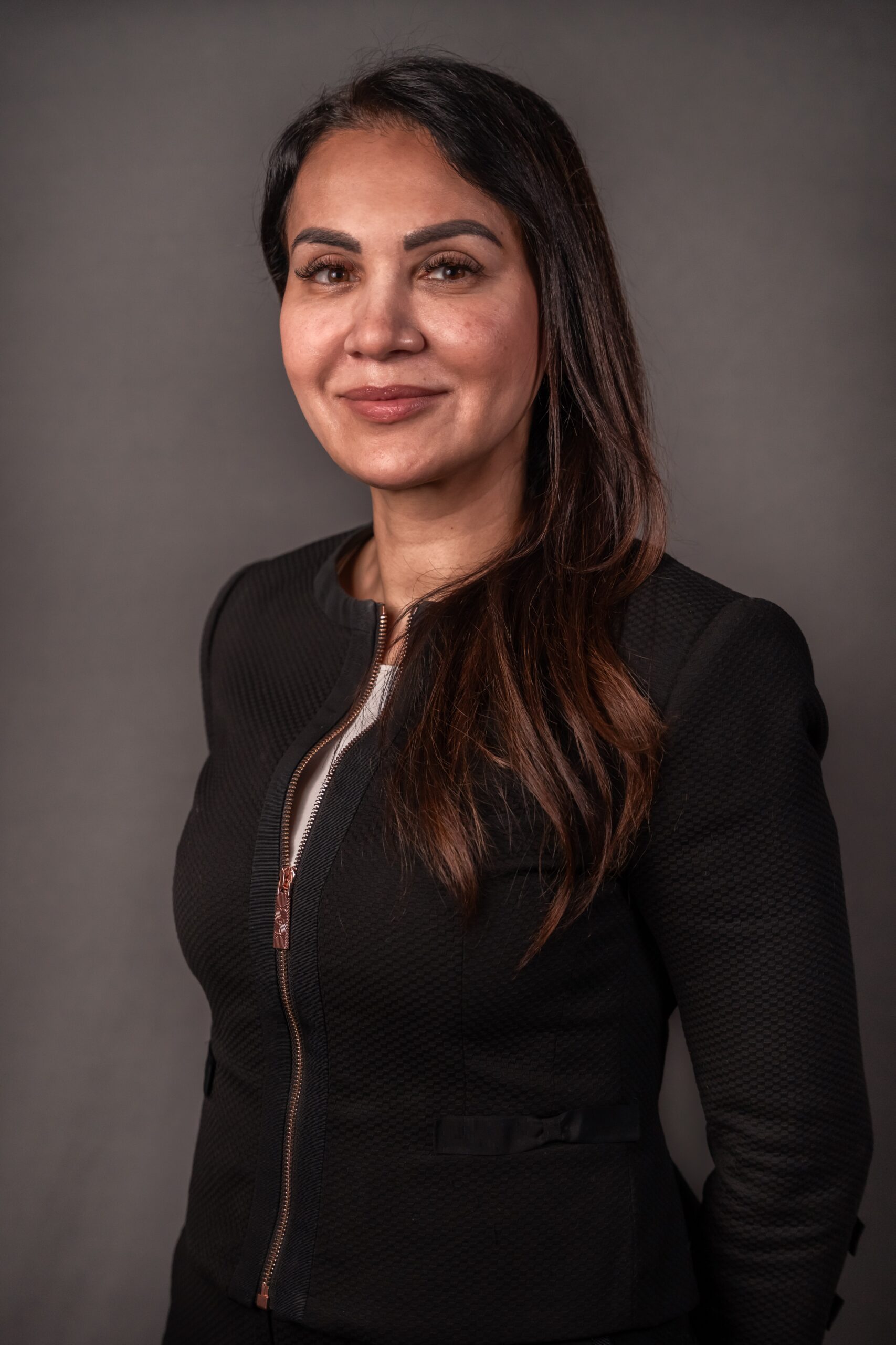 Bildet forestiller en kvinne med halvlangt brunt hår. Hun har på seg sort overdel, og ser inn i kameraet. Bakgrunnen er mørkegrå. Kvinnen heter Kanwal Suleman, og er advokat.