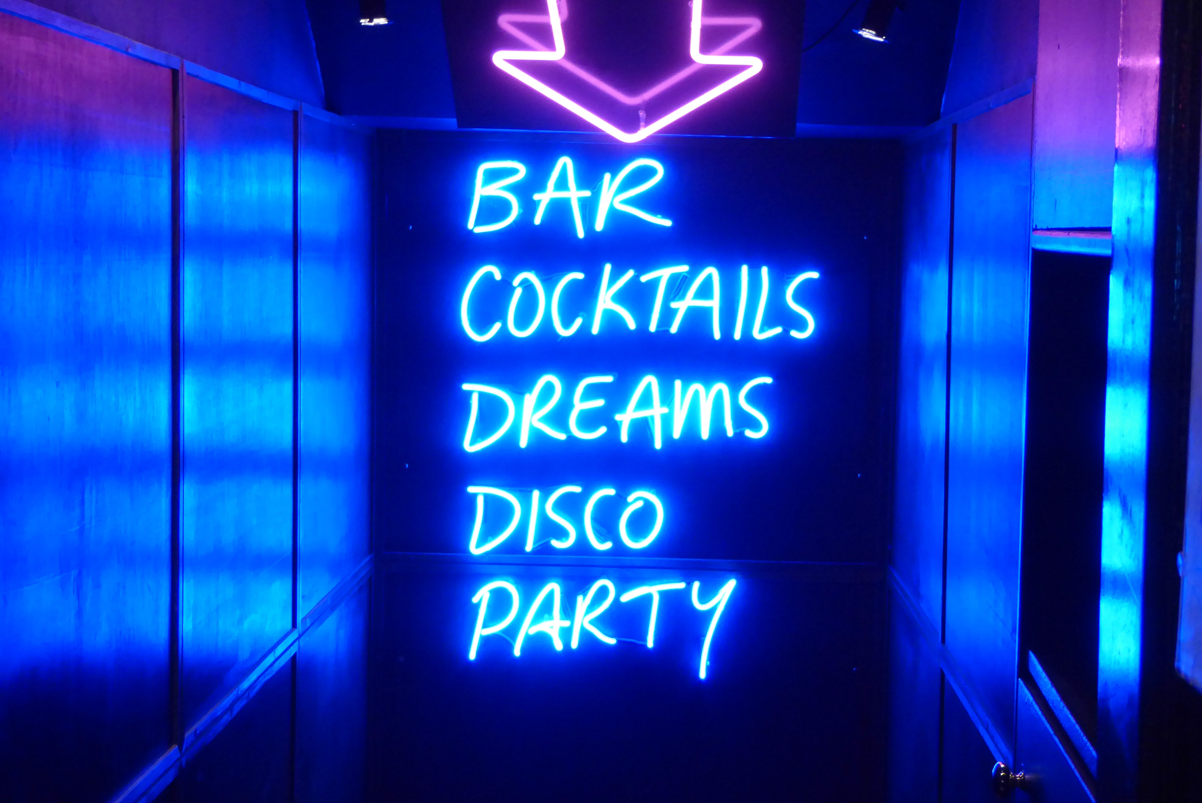 Bildebeskrivelse: Neonskilt i blått og rosa med teksten bar cocktails dreams disco party