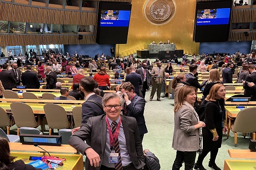 Ombud Bjørn Erik Thon poserer foran stor folkemengde inne i FN-bygget i New York