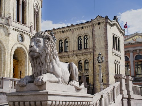 Foto av Stortinget i Oslo, med en statue av en løve i front
